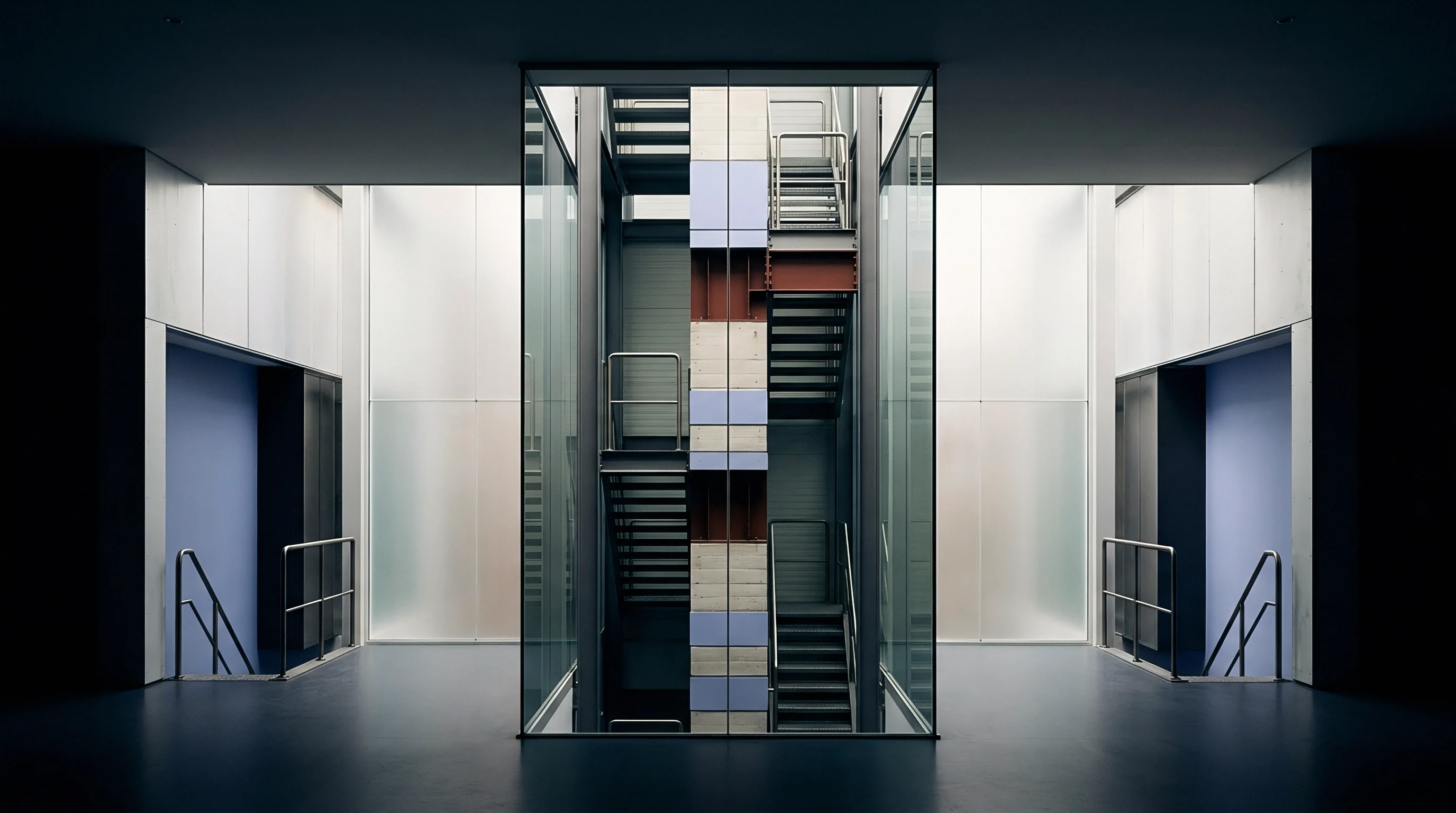 Interior architecture reveals a multi-level industrial facility, integrating steel stairwells within a clear glass shaft.