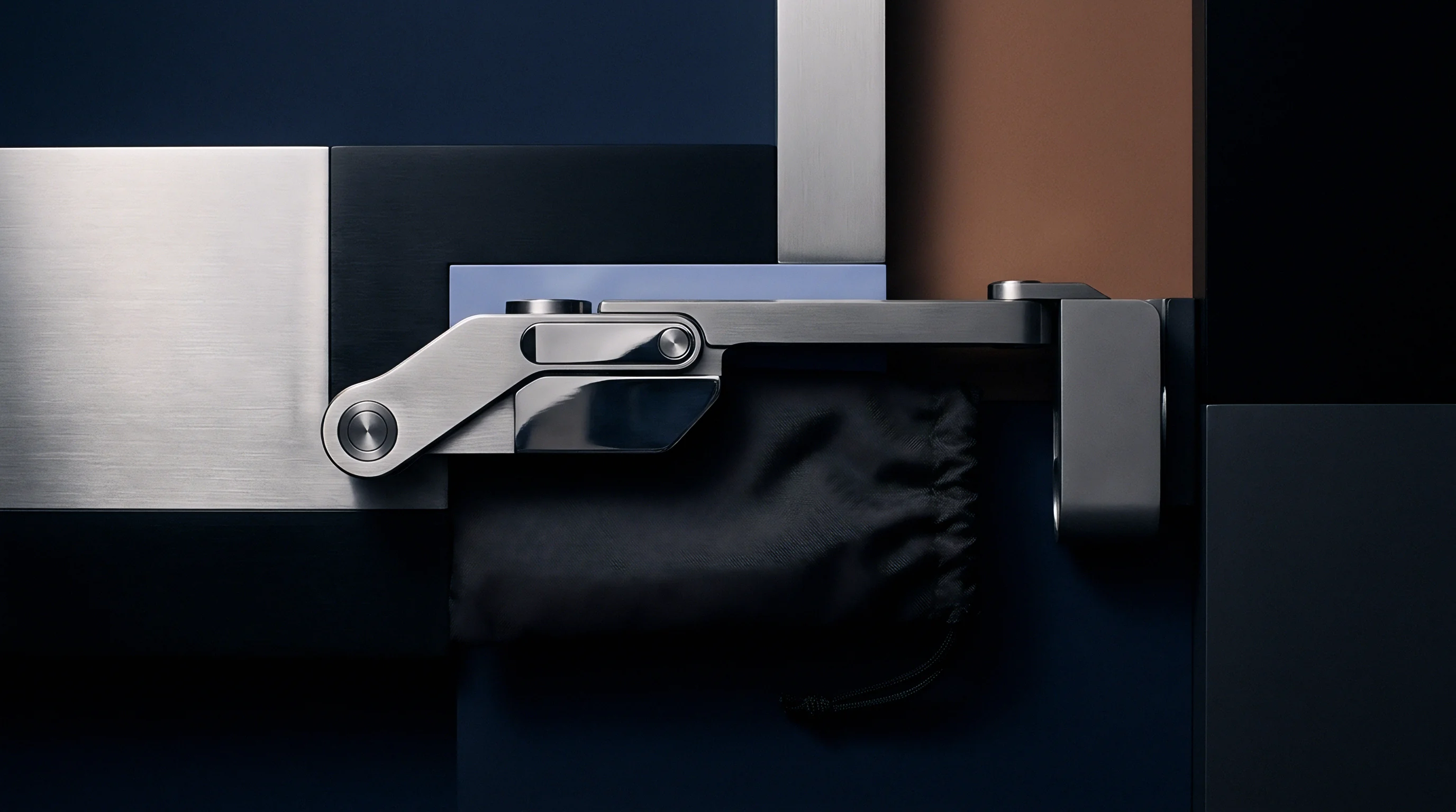 Machined metallic hardware component rests beside a textile pouch against structured industrial panels of steel and matte black polymers.